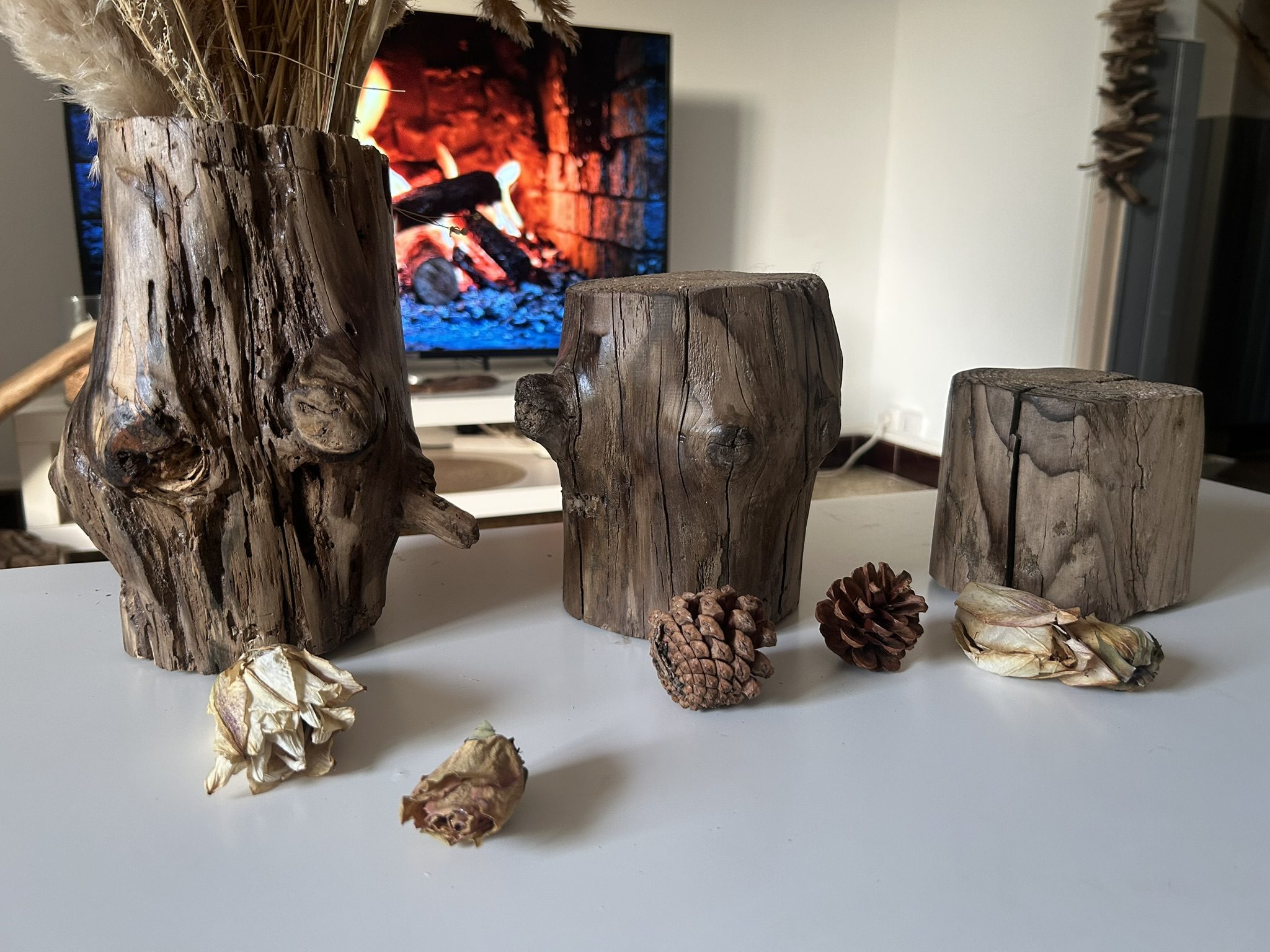 Vase en bois flotté avec deux supports en bois brut, décoration chaleureuse avec feu de cheminée en arrière-plan